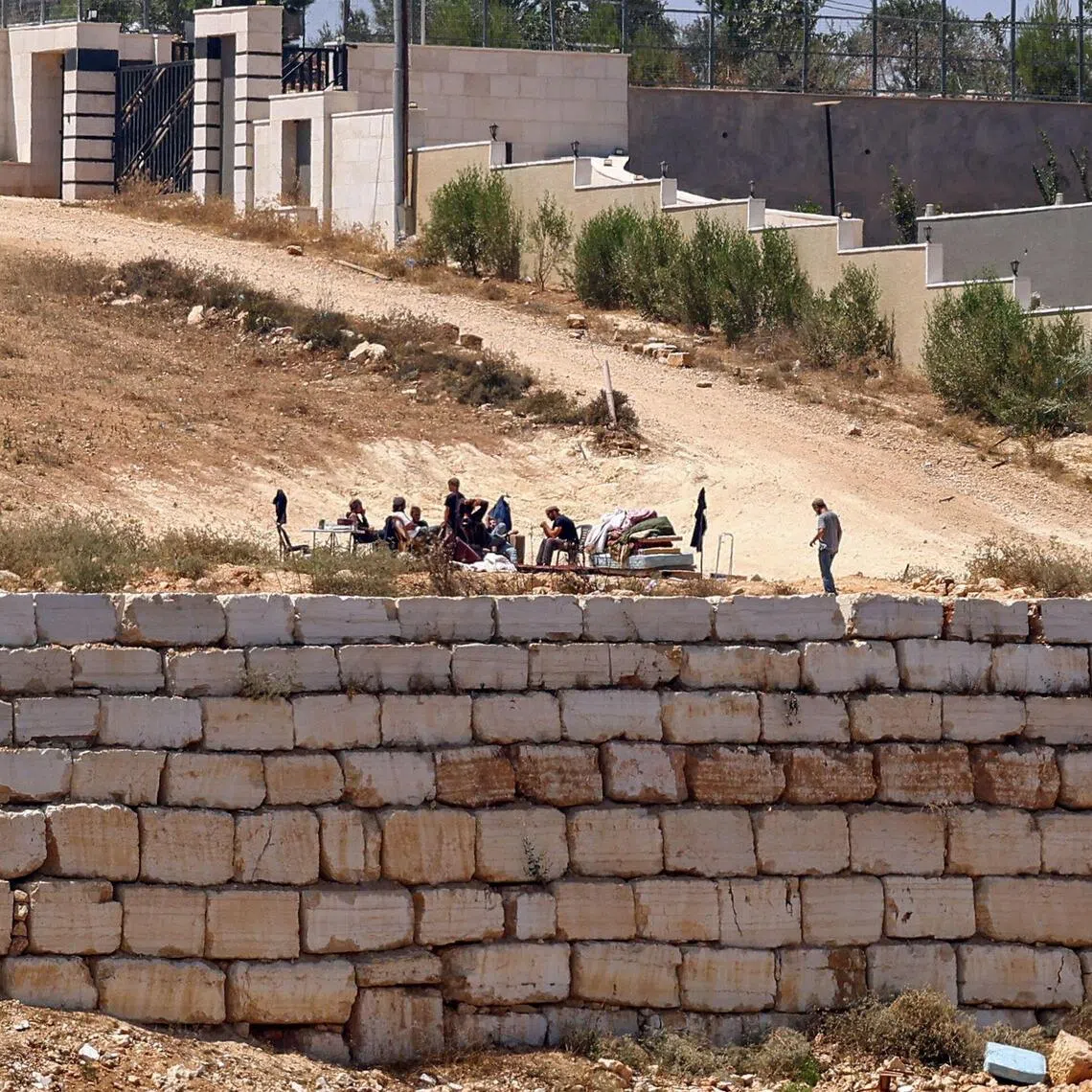 Israeli settlers gather in front of Palestinian houses in the village of Qusra, south of Nablus, in the occupied West Bank, on Aug 12.