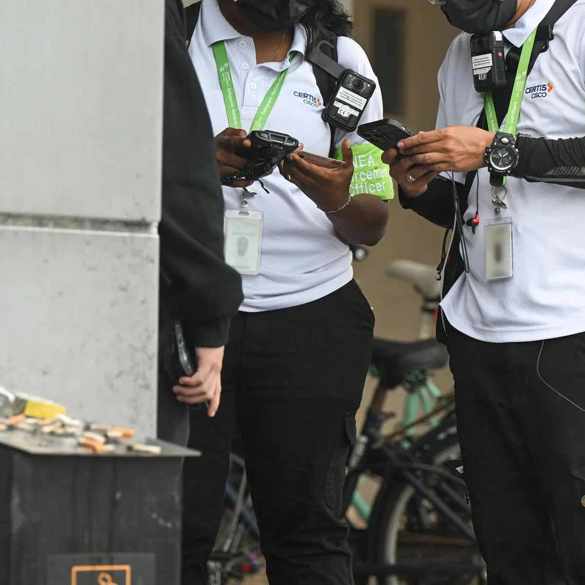 ST20240503_202499561572 wxnea06 Azmi Athni// Two National Environment Agency (NEA) enforcement officers catching a smoker who was smoking under a shelter along Causeway Point shopping mall on May 3. Embargo until May 6, 11am. ST PHOTO: AZMI ATHNI