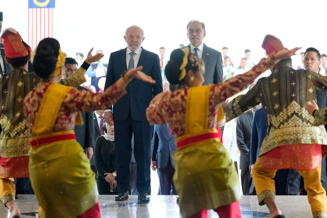Brazilian Luiz Inacio Lula da Silva (left) and Malaysian Prime Minister Anwar Ibrahim being welcomed by traditional dance performers in Putrajaya, Malaysia, on Oct 25.