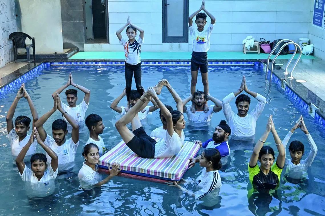 Youths taking part in a yoga practice session in a swimming pool on the eve of the International Day of Yoga, in Amritsar on June 20, 2024.