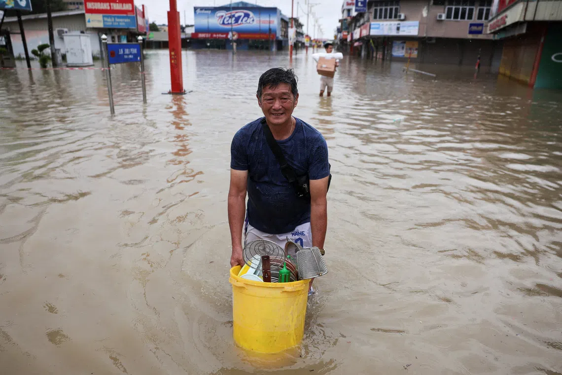 People wading through flood water with their belongings in Kangar after heavy rain in the northern states of Malaysia.