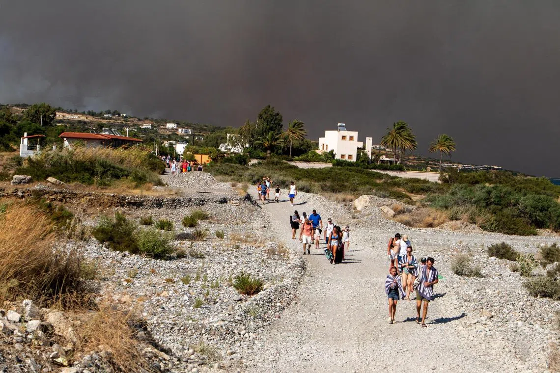 Tourists are being evacuated as wildfire burns near Lindos, on the island of Rhodes, Greece, July 22, 2023.  REUTERS