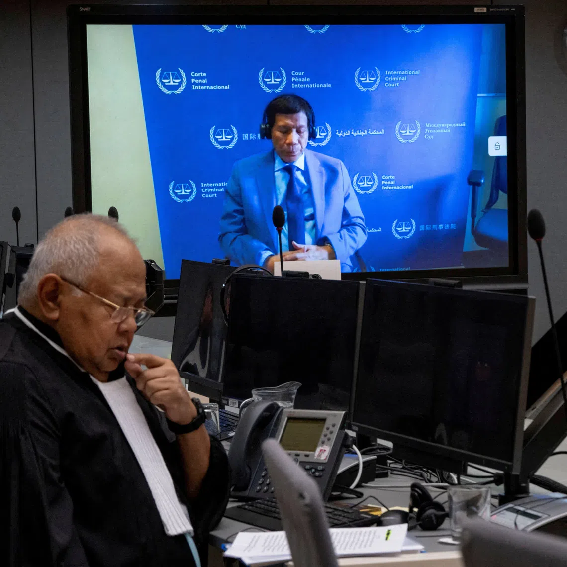 Former Philippine president Rodrigo Duterte (on screen) with his lawyer in an ICC courtroom in March.