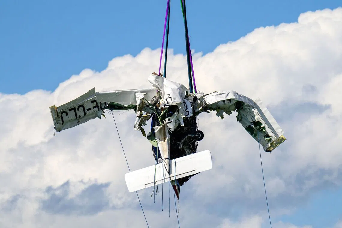 TOPSHOT - The wreckage of a small aircraft, that crashed on August 26 into Lake Attersee, hangs in the air as it is retrieved from the lake in the Steinbach area, Upper Austria, on August 31, 2026. The propeller plane that crashed into Lake Attersee near Steinbach last Wednesday, August 26 resulting in the deaths of its two passengers, was recovered on August 31 from a depth of 160 meters. (Photo by Werner KERSCHBAUMMAYR / various sources / AFP) / Austria OUT