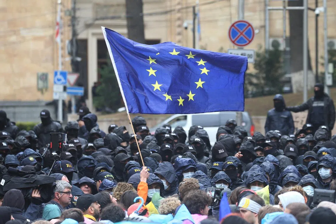 A demonstrator holds a European Union flag in front of law enforcement officers during a rally to protest against a bill on \"foreign agents\" in Tbilisi, Georgia, May 14, 2024. REUTERS/Irakli Gedenidze