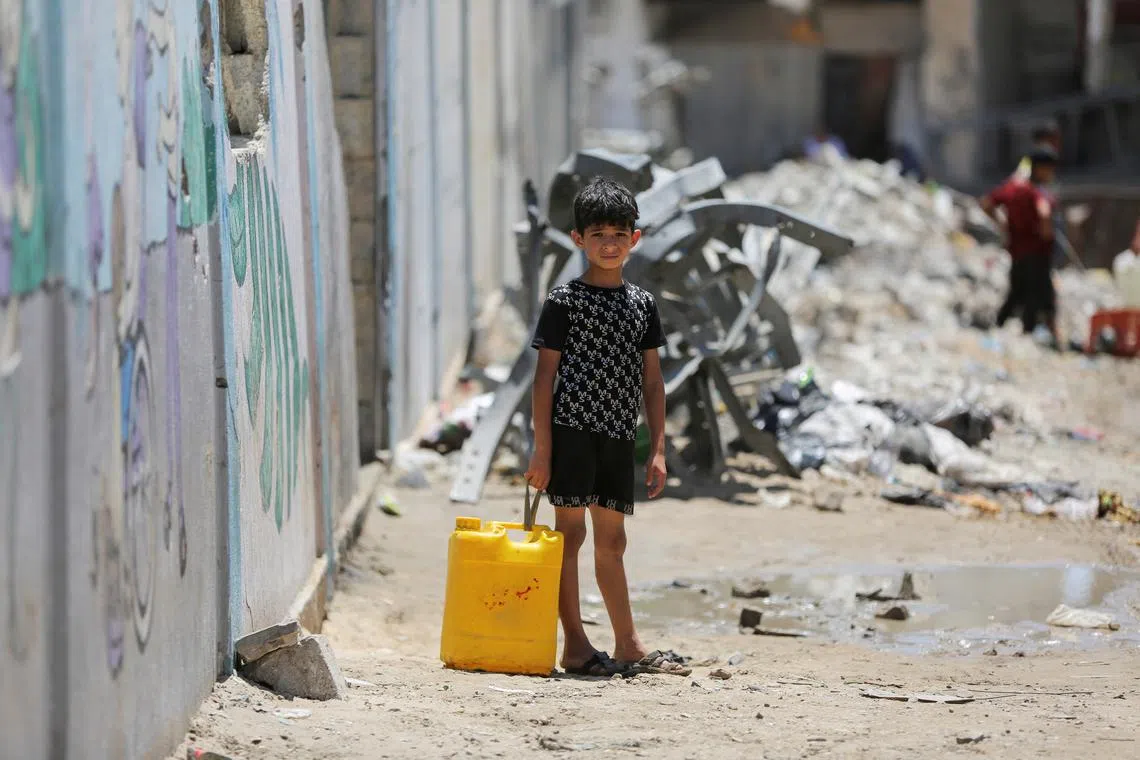 A child stands holding a water container as Palestinians gather to collect water amid shortages during the ongoing conflict between Israel and Hamas, in Khan Younis in the southern Gaza Strip, July 29, 2024. REUTERS/Hatem Khaled