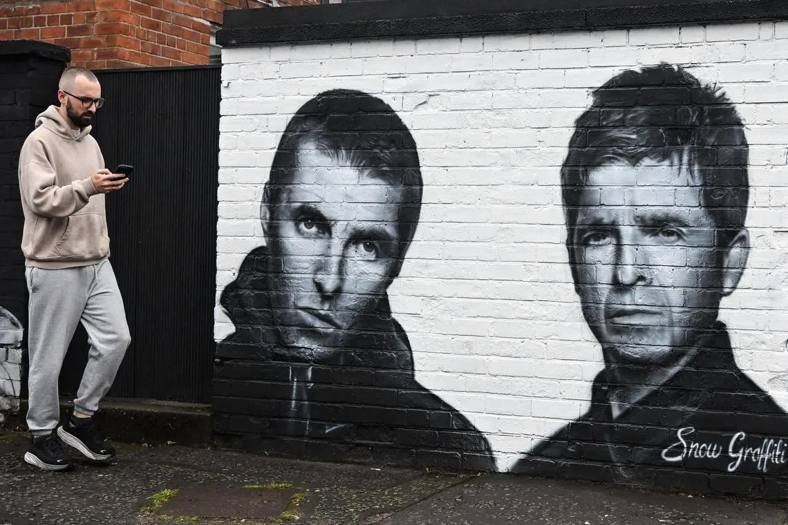 A pedestrian walks past a mural created by artist Scott Wilcock aka Snow Graffiti, depicting Liam Gallagher (L) and Noel Gallagher (R) members of the British rock band Oasis, and painted outside the pub Whitefield, near Heaton Park, in Manchester, northern England, on Sept 2. 