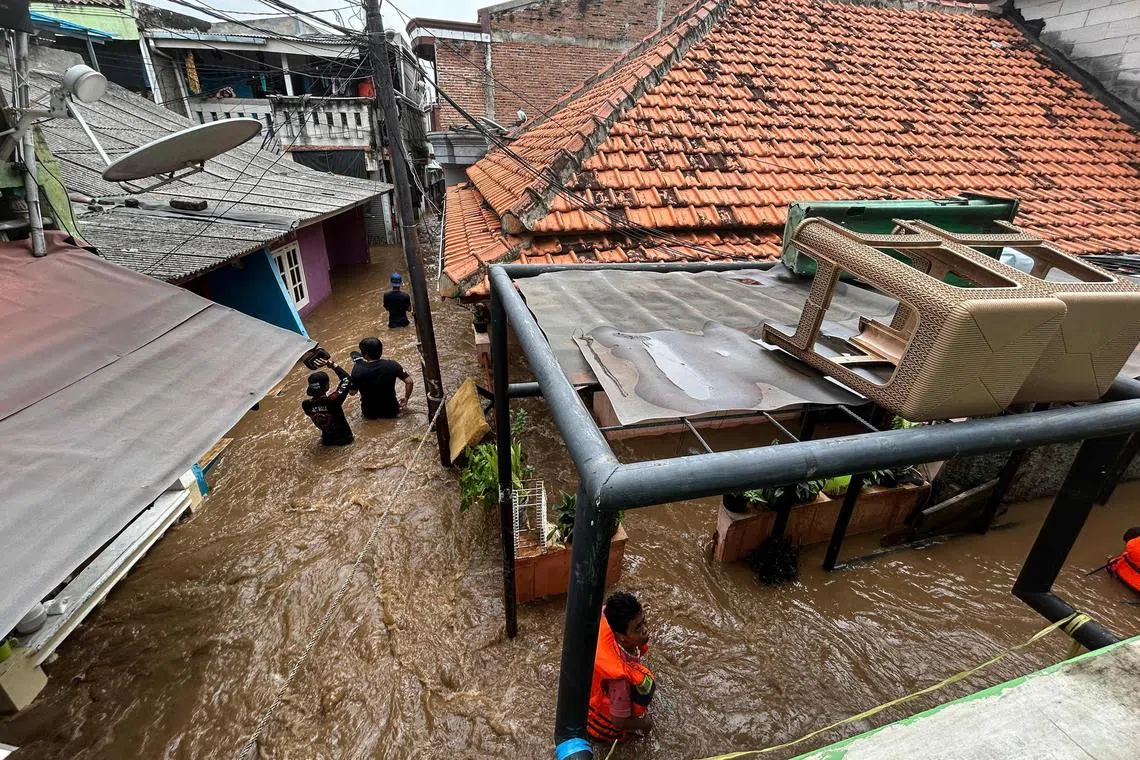 Residents, whose homes are flooded, evacuate by holding onto a rope in the Jatinegara district, Jakarta on March 4.