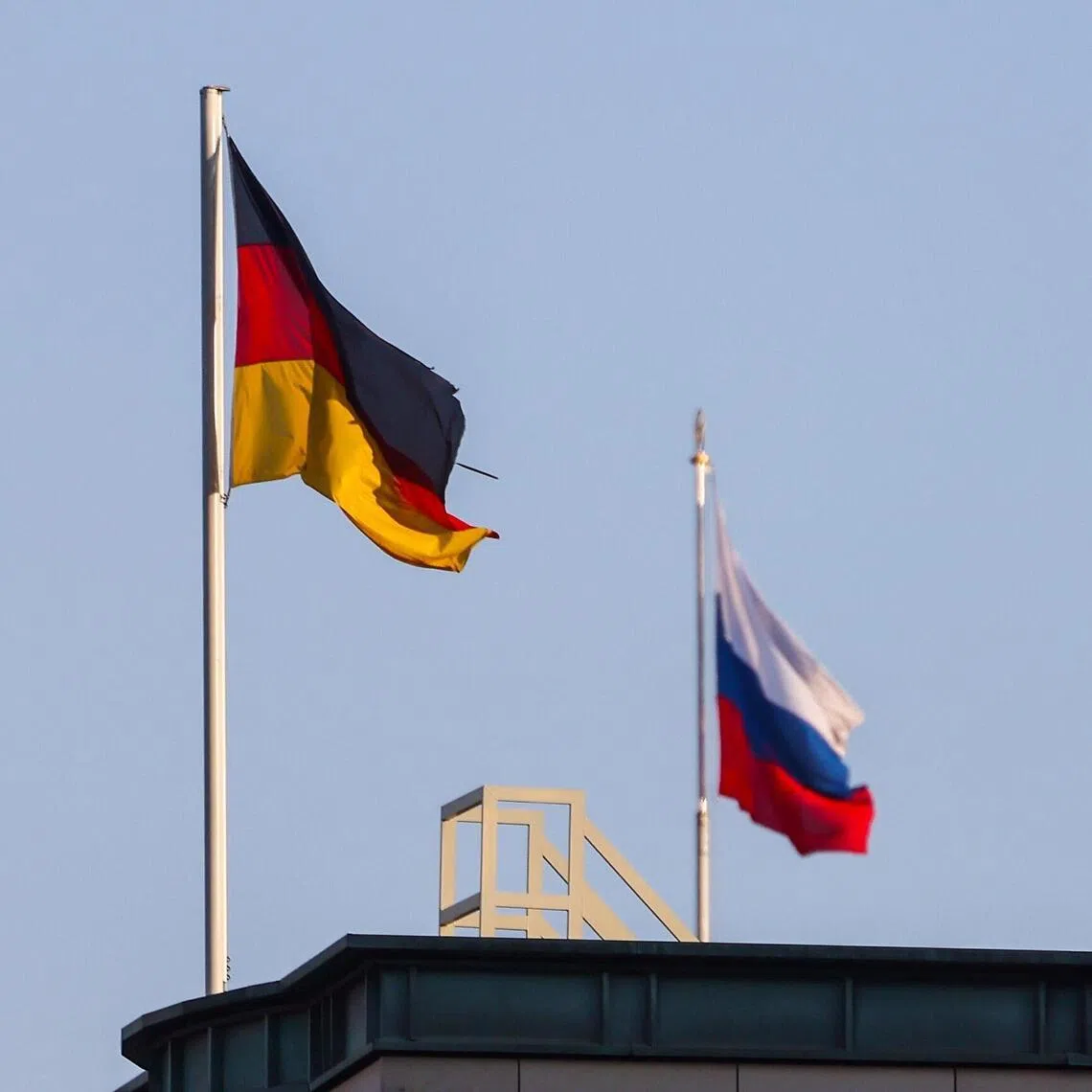 A German flag (left) flies next to the Russian flag on the roof of the Russian embassy in Berlin, Germany.