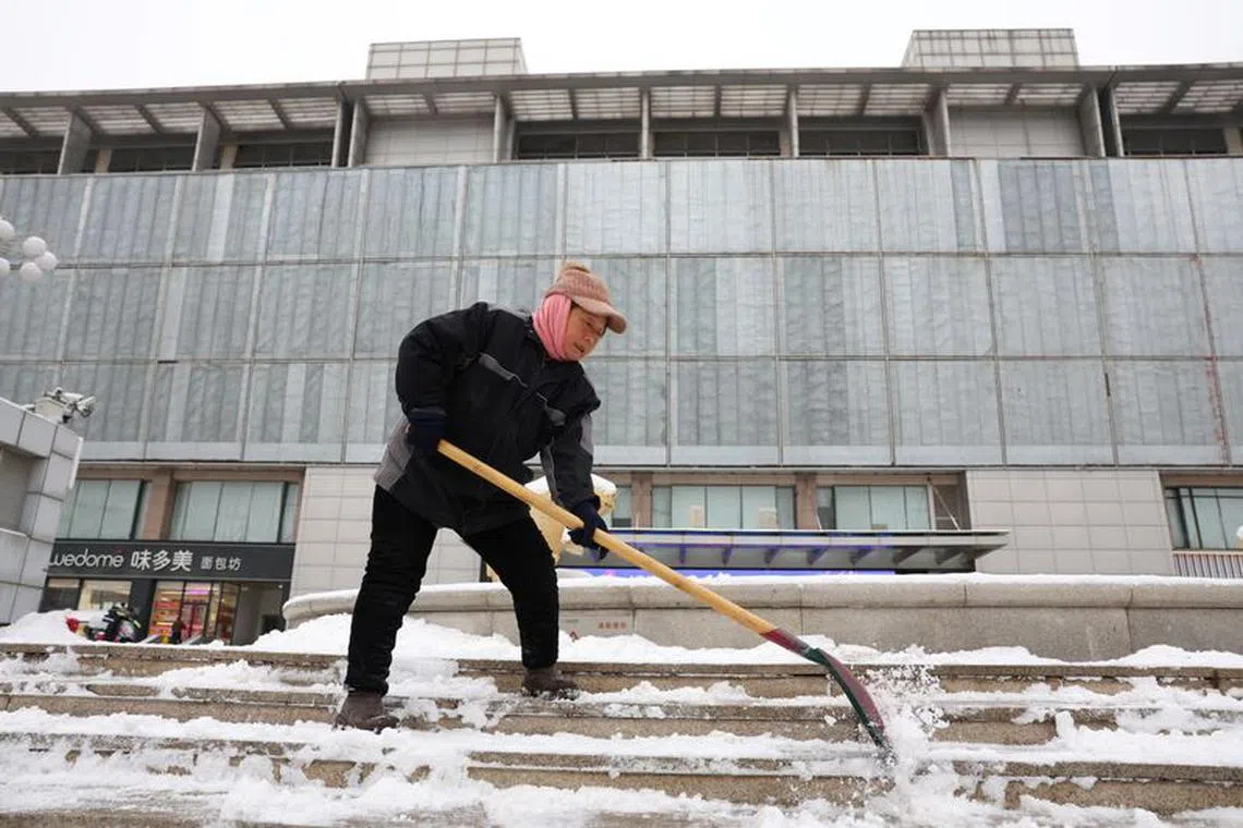 A worker shovels snow on stairs in front of a mall amid snowfall in Beijing, China December 14, 2023. REUTERS/Tingshu Wang