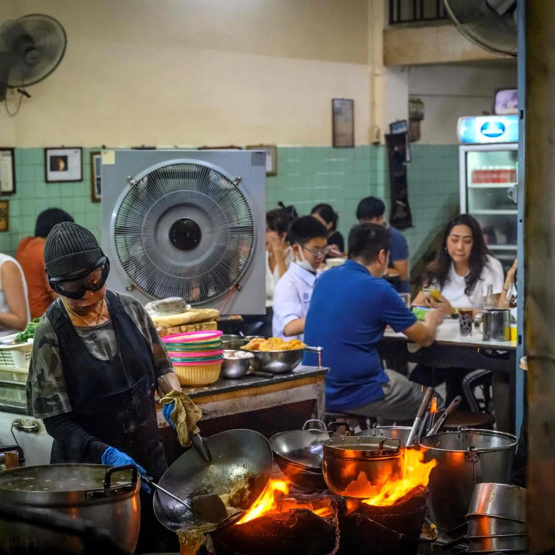 (FILES) The Queen of Street Food and Michelin star chef Jay Fai (L foreground) cooks at her restaurant in downtown Bangkok on July 15, 2020. A Thai cook who became the first Bangkok street food vendor to earn a coveted Michelin star has said in an interview video posted online on November 27, 2024 she plans to retire, possibly as early as next year. (Photo by Mladen ANTONOV / AFP)