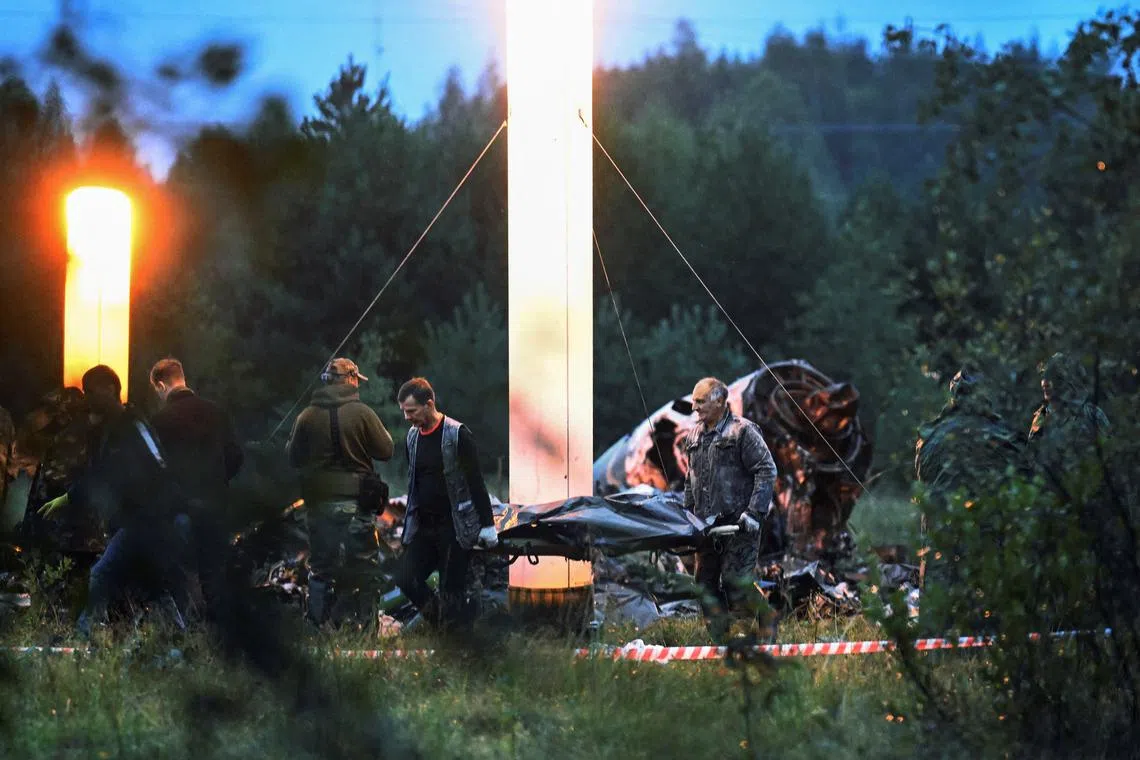 Emergency specialists carry a body bag near wreckages of the private jet at the crash site in the Tver region, Russia, on Aug 24, 2023. 