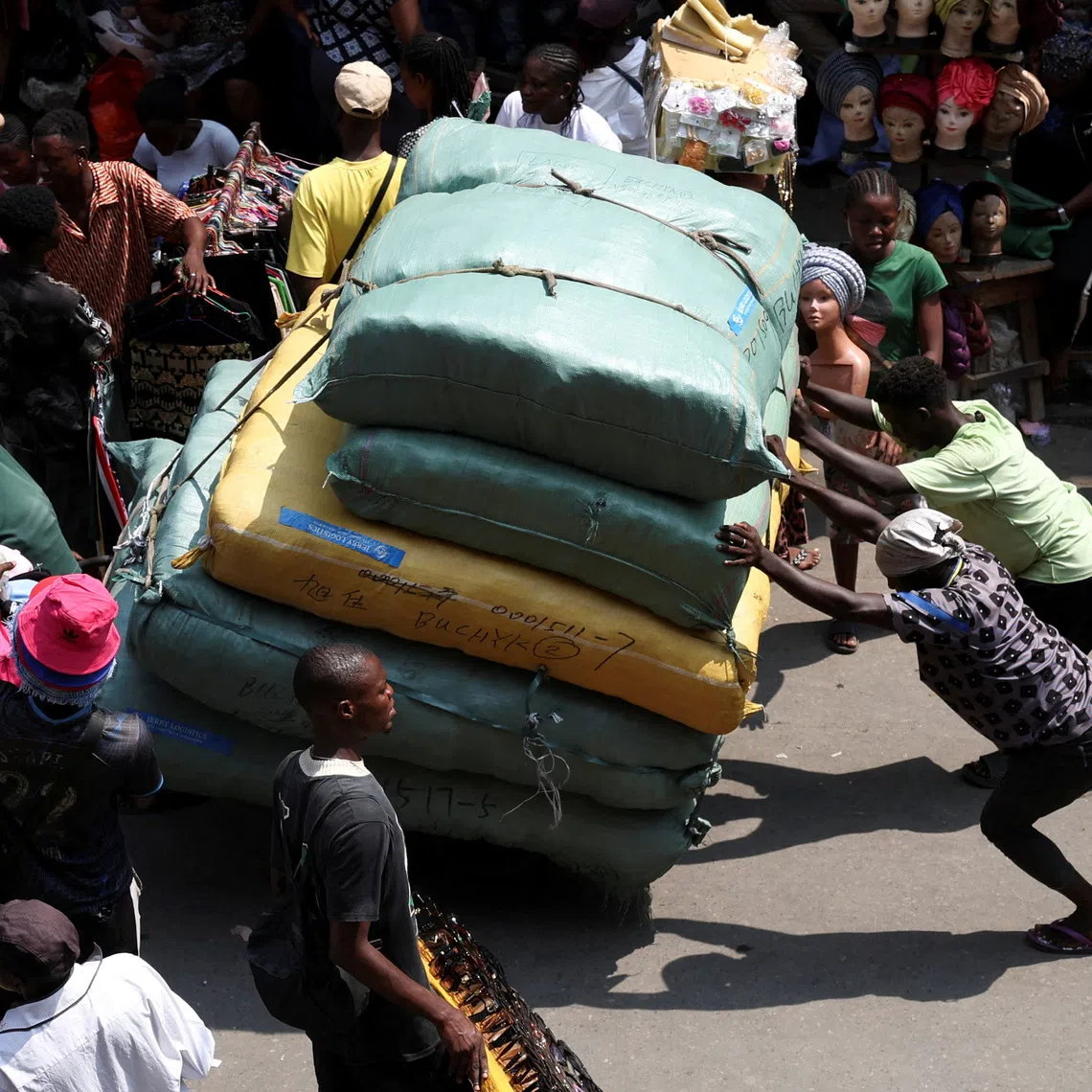 FILE PHOTO: People push a cargo cart through Balogun Market in the Marina business district of Lagos, Nigeria, December 2, 2025. REUTERS/Sodiq Adelakun/File Photo