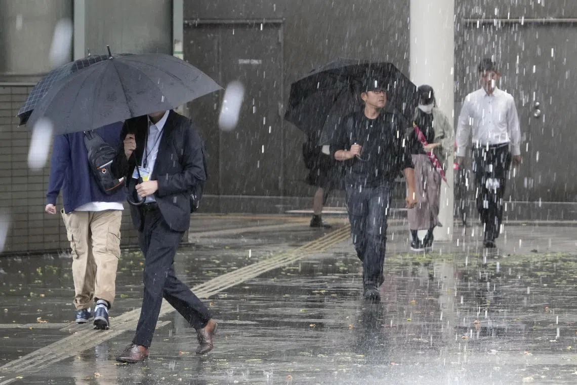 epa10847846 People walk under heavy rainfall generated by tropical storm Yun-yeung in Chiba, near Tokyo, Japan, 08 September 2023. The tropical storm generated heavy rain and disrupted traffic, as the Japan Meteorological Agency warned of flooding in low-lying areas.  EPA-EFE/FRANCK ROBICHON