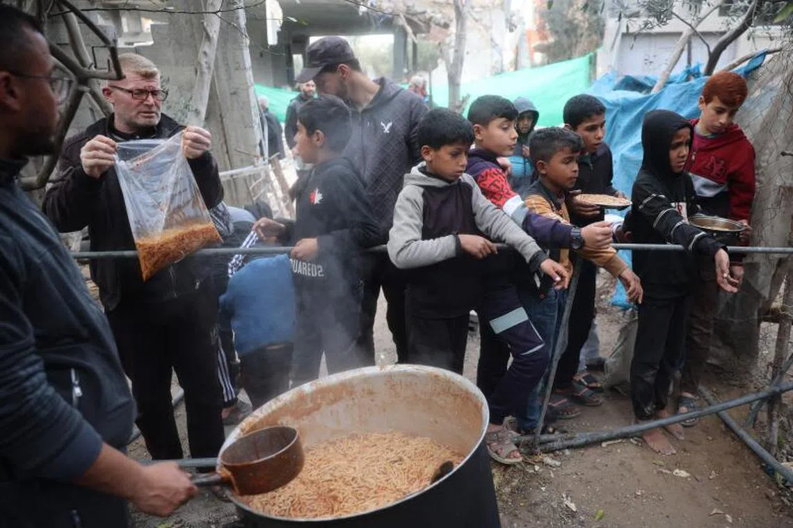 Palestinian children wait for a meal during food distribution at a charity kitchen at the Nuseirat refugee camp in the central Gaza Strip on March 3, 2025, during the holy Muslim fasting month of Ramadan. (Photo by Eyad BABA / AFP)
