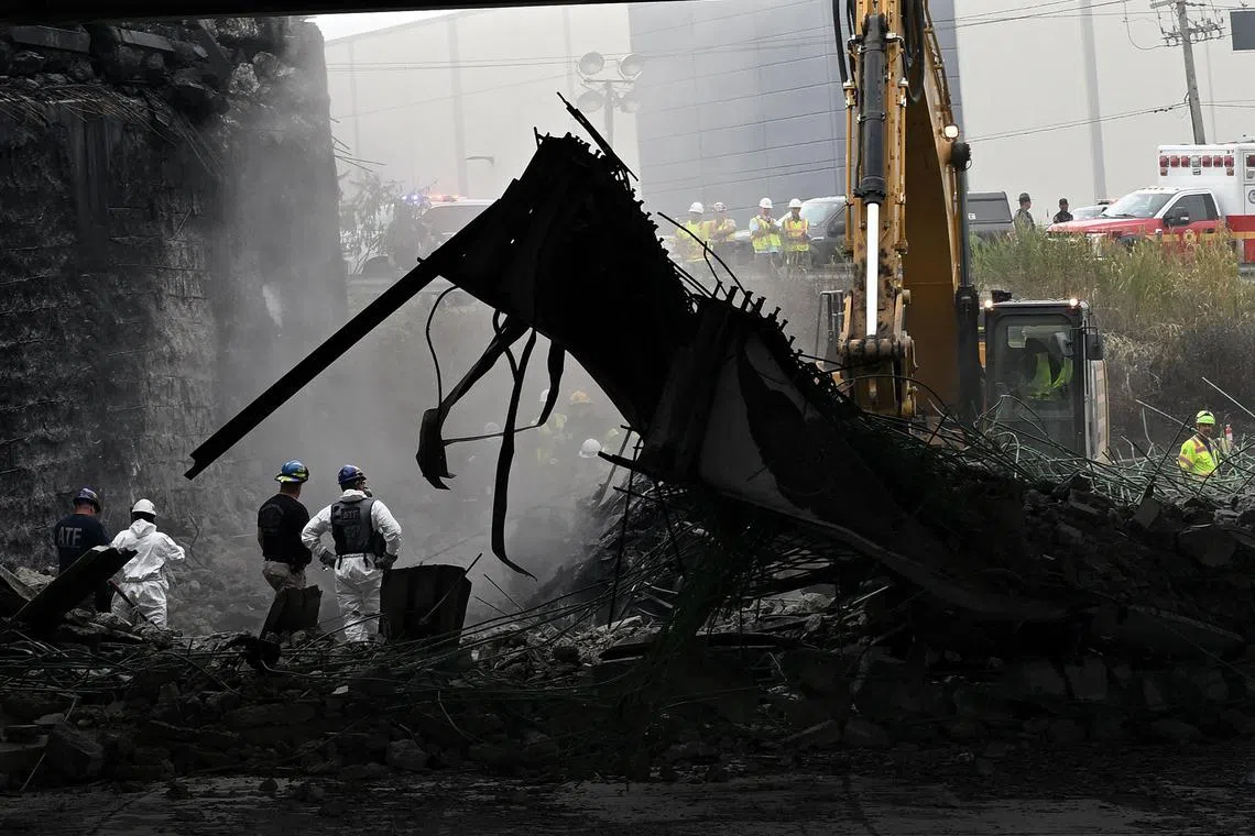  Workers inspect and clear debris from a section of the bridge that collapsed on Interstate 95 after an oil tanker explosion.
