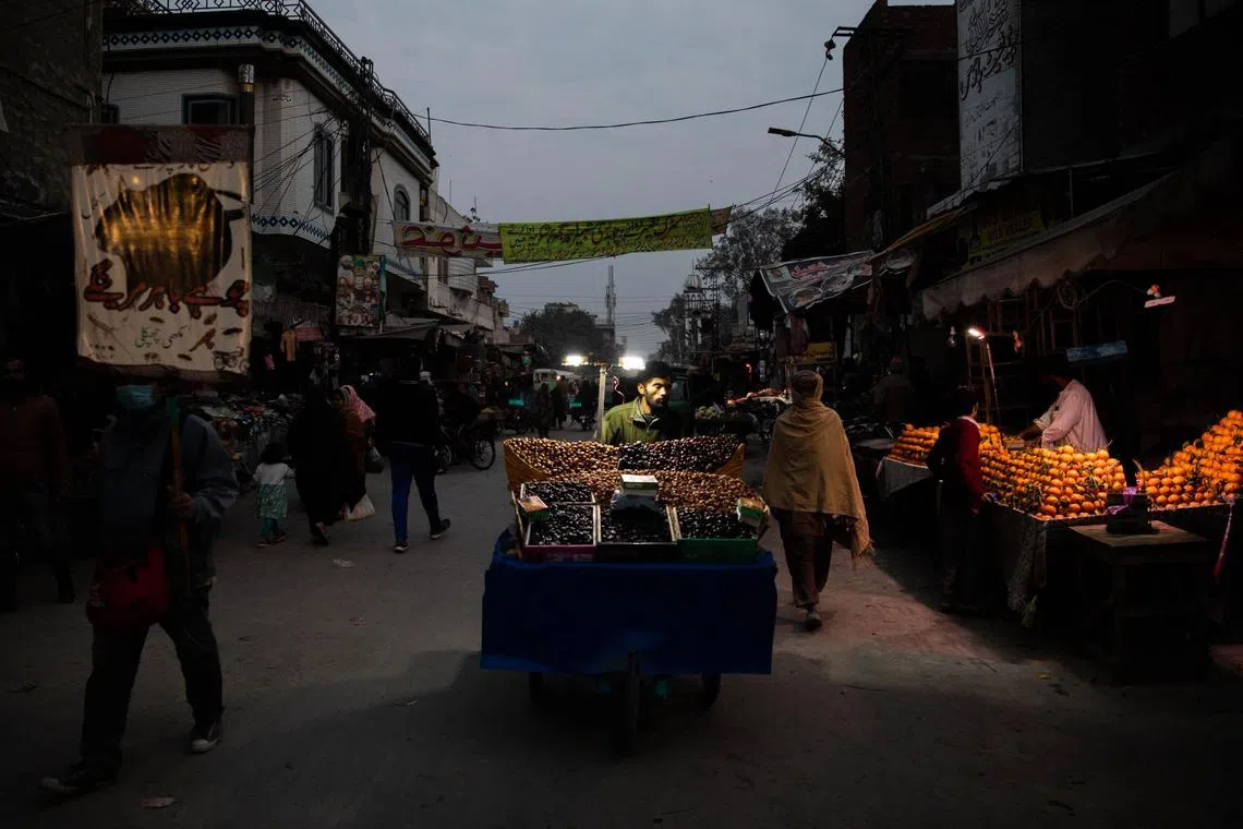 Vendors sell fruit under lights lit by batteries in Lahore, Pakistan, on Jan 23, 2023.