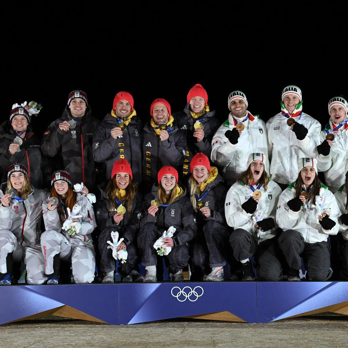 Milano Cortina 2026 Olympics - Luge - Team Relay Victory Ceremony - Cortina Sliding Centre, Cortina d'Ampezzo, Italy - February 12, 2026. Gold medallists Julia Taubitz of Germany, Tobias Wendl of Germany, Tobias Arlt of Germany, Max Langenhan of Germany, Dajana Eitberger of Germany and Magdalena Matschina of Germany celebrate on the podium after winning the Team Relay with silver medallists Lisa Schulte of Austria, Thomas Steu of Austria, Wolfgang Kindl of Austria, Jonas Mueller of Austria, Selina Egle of Austria and Lara Michaela Kipp of Austria and bronze medallists Verena Hofer of Italy, Emanuel Rieder of Italy, Simon Kainzwaldner of Italy, Dominik Fischnaller of Italy, Andrea Voetter of Italy and Marion Oberhofer of Italy REUTERS/Annegret Hilse