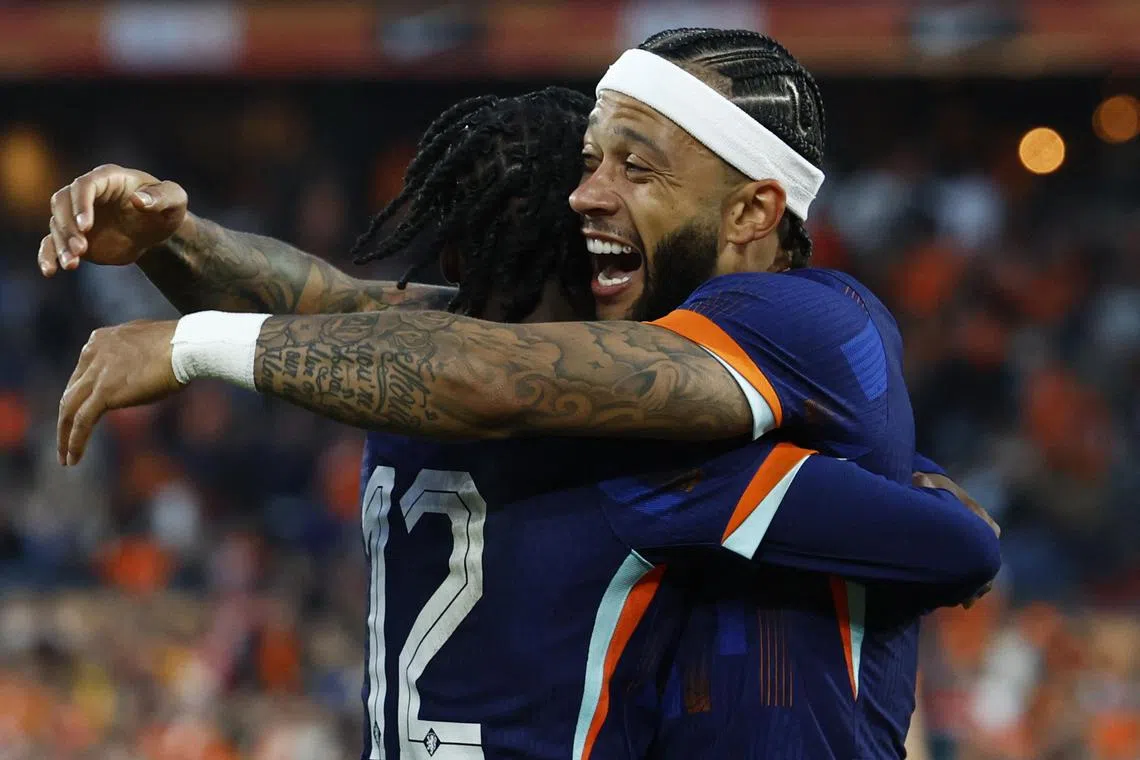 Netherlands' Memphis Depay celebrates scoring their first goal with Jeremie Frimpong.