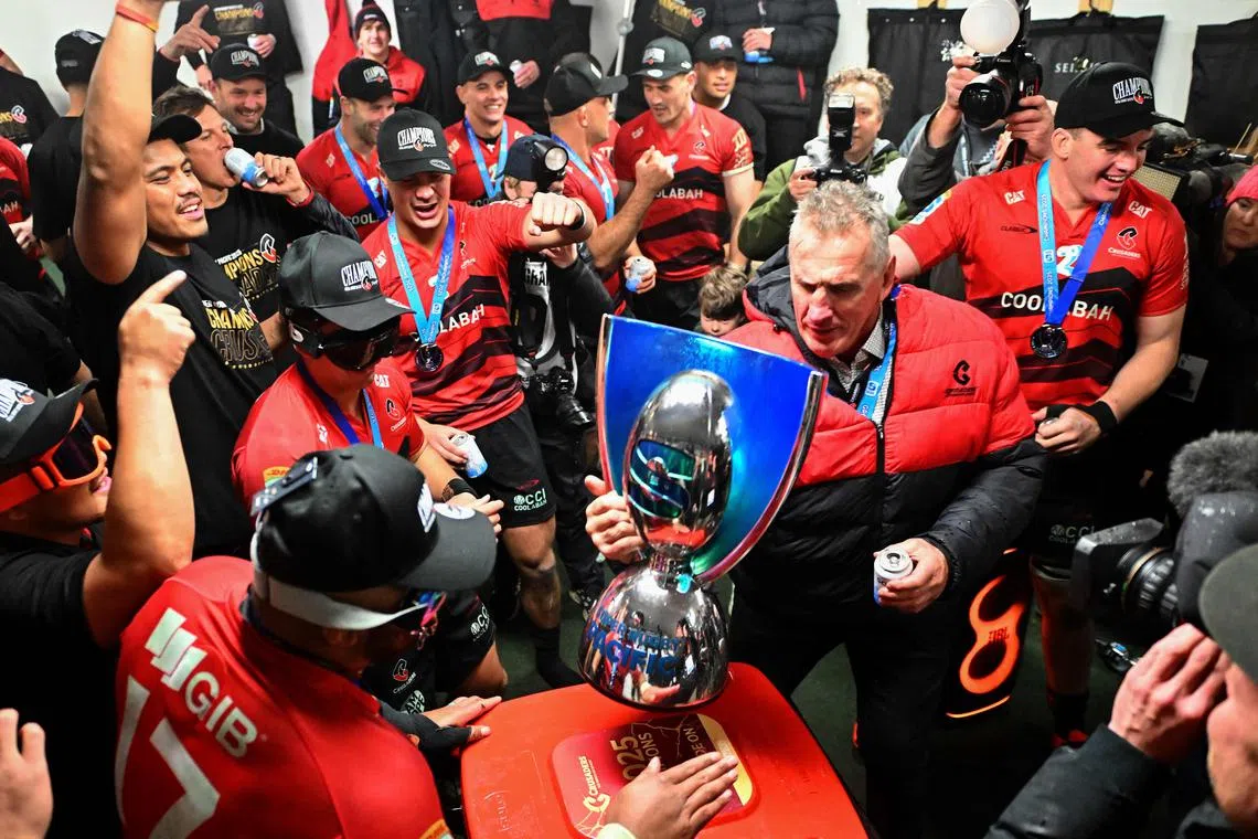 Crusaders head coach Rob Penney and players celebrate with the trophy in the dressing room after their victory over the Chiefs in the Super Rugby Pacific grand final at Apollo Projects Stadium in Christchurch on June 21, 2025.