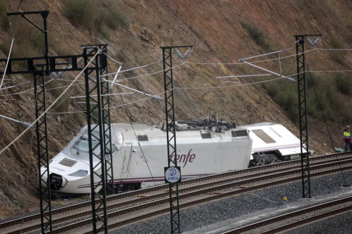 FILE PHOTO: Workers stand beside the train engine at the site of a train crash in Santiago de Compostela, northwestern Spain, July 26, 2013. REUTERS/Miguel Vidal/File Photo