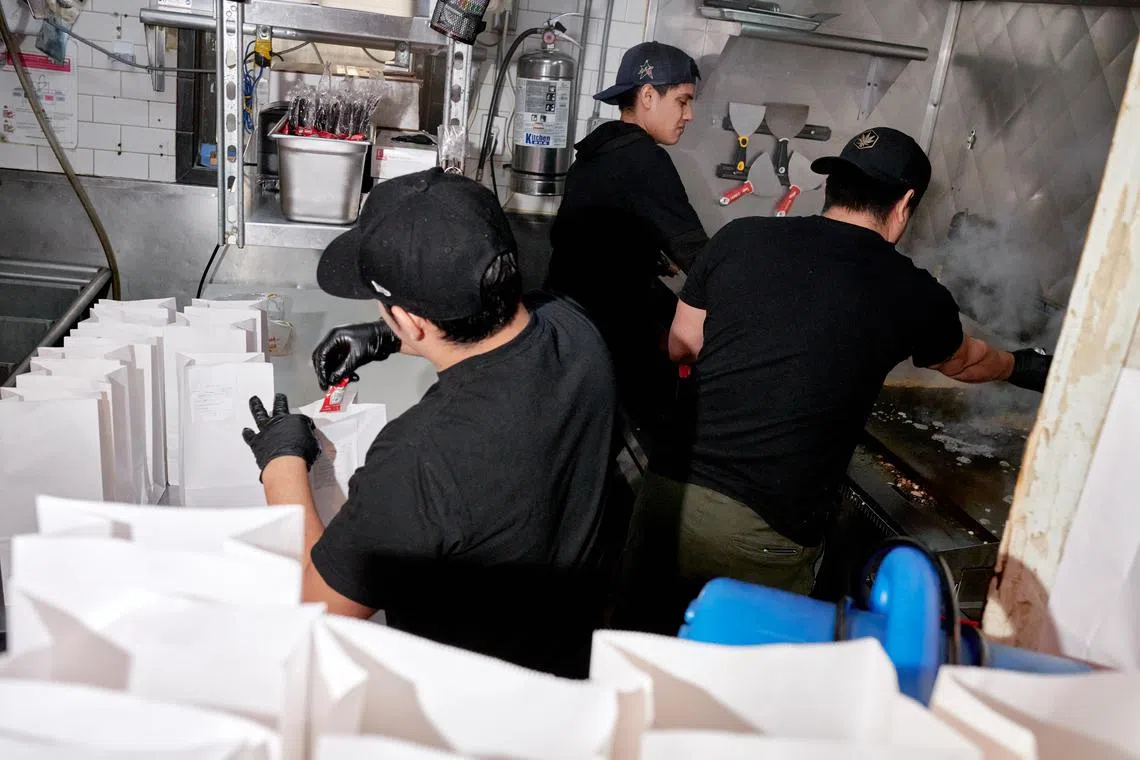 Workers fill orders at 7th Street Burger, which opened in 2021 and quickly took off, in Manhattan on Feb. 6, 2024. After drooping in 2022, the output of U.S. businesses per worker has surged. Economists wonder if the trend can continue, and who will benefit most. (Gabby Jones/The New York Times)
