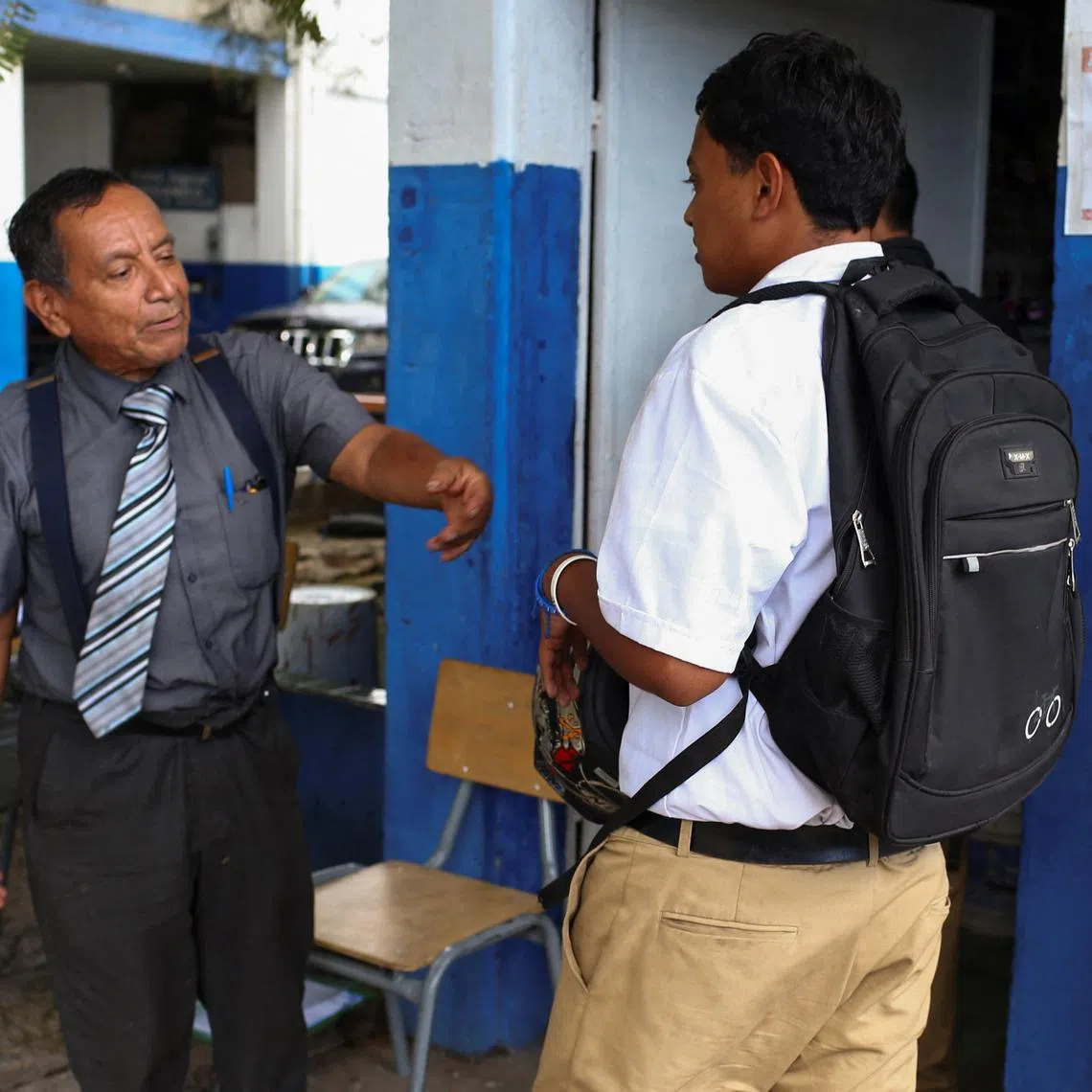 Principal Oscar Melara checks a student's uniform at Instituto Nacional Tecnico Industrial, as regulations over students' appearance and behaviour are enforced following a memorandum by the Ministry of Education, in San Salvador, El Salvador, August 21, 2025. REUTERS/Jose Cabezas