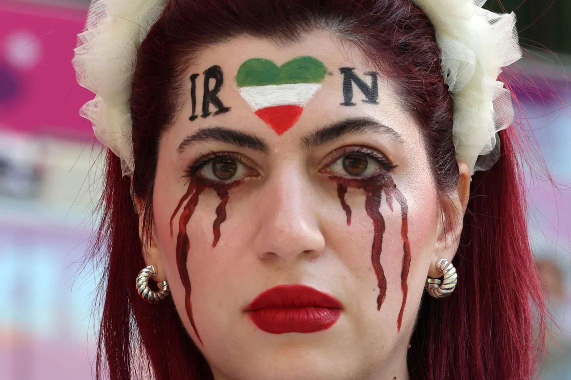 An Iran supporter in Doha with her face made up to show tears of blood under a heart. 