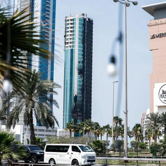 Vehicles drive past a building that was damaged by an Iranian drone attack in Seef, Manama, Bahrain, on March 1, 2026.