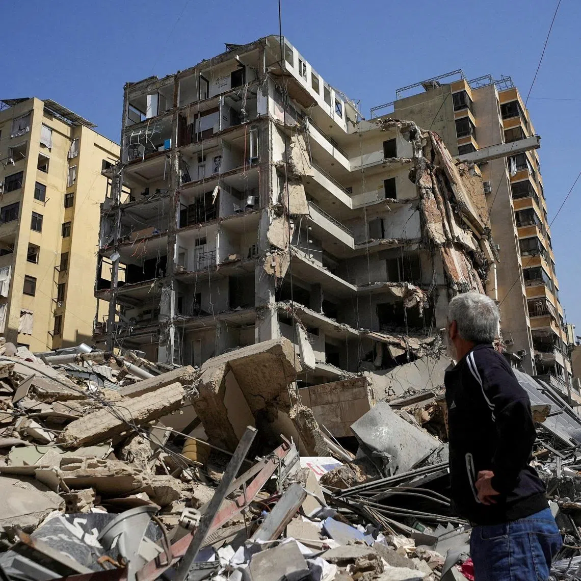 FILE PHOTO: A man stands next to a damaged building in the aftermath of Israeli strikes, amid an escalation between Hezbollah and Israel, amid the U.S.-Israeli conflict with Iran, in Beirut's southern suburbs, Lebanon, March 12, 2026. REUTERS/Stringer/File Photo