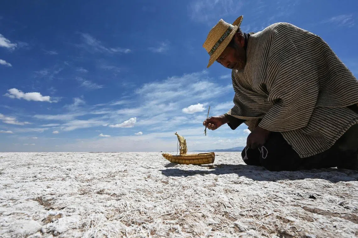 Felix Mauricio, a member of the Uru Murato Indigenous community, puts a miniature replica of a boat known as a "totora boat" on a desert at the site of former Lake Poopo, near the village of Punaca Tinta Maria, province of Oruro, Bolivia, on October 15, 2022. - Lake Poopo, once Bolivia's second-largest, has largely disappeared, taking with it a centuries-old culture reliant entirely on its bounty. 