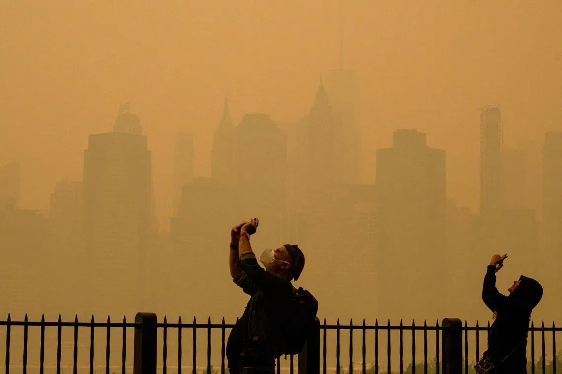 People taking photos of the sun as smoke from the wildfires in Canada cause hazy conditions in New York City on June 7, 2023. 