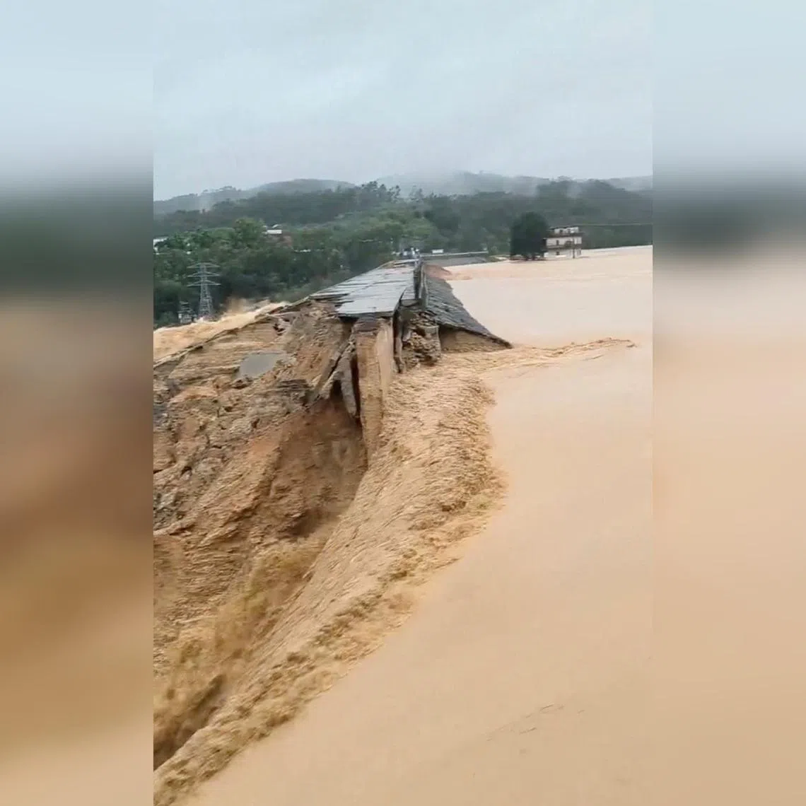 In this still image obtained from a social media video, water flows through a burst reservoir dam wall, following heavy rain in Heng County, Nanning, China, on July 6.