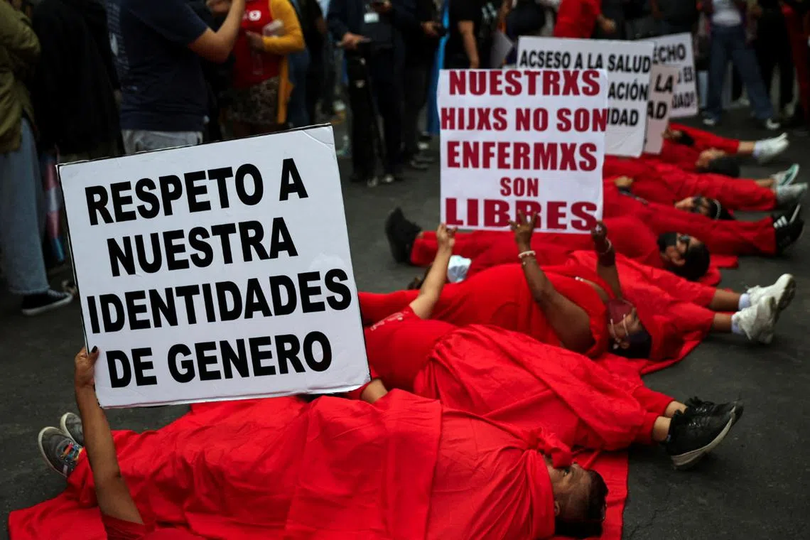 A group of protesters carry signs at a protest by the LGBTQI community against a new government decree listing transsexualism as a \"mental disorder\", in front of the Ministry of Health, in Lima, Peru May 17, 2024. REUTERS/Sebastian Castaneda