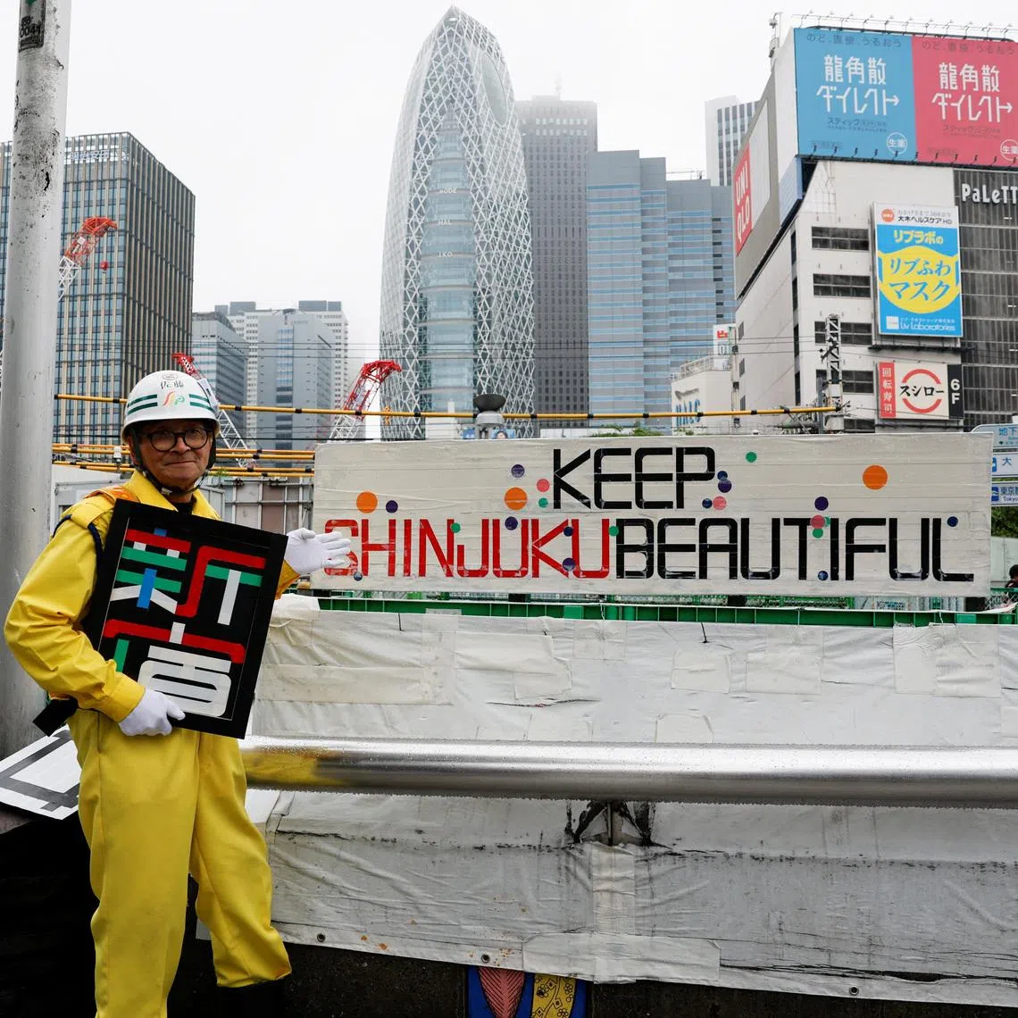 Mr Shuetsu Sato poses with duct-tape signs he made outside Shinjuku Station's east exit in Tokyo on May 1.