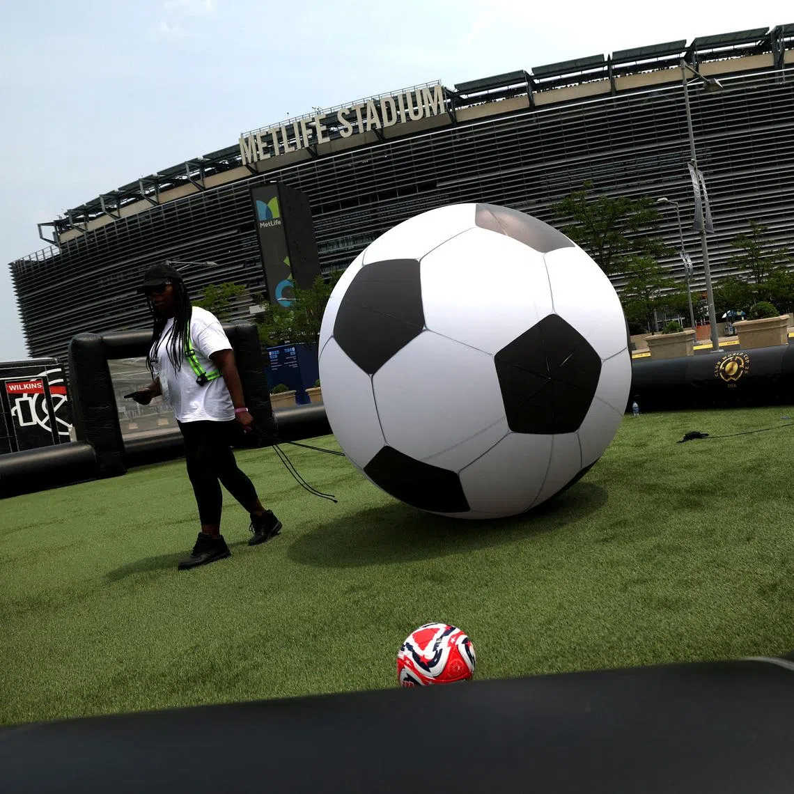 FILE PHOTO: Soccer Football - Club World Cup - Previews - MetLife Stadium, East Rutherford, New Jersey, U.S. - June 13, 2025   General view of a member of staff with a giant ball on a pitch outside the stadium ahead of the Club World Cup REUTERS/Susana Vera/File Photo