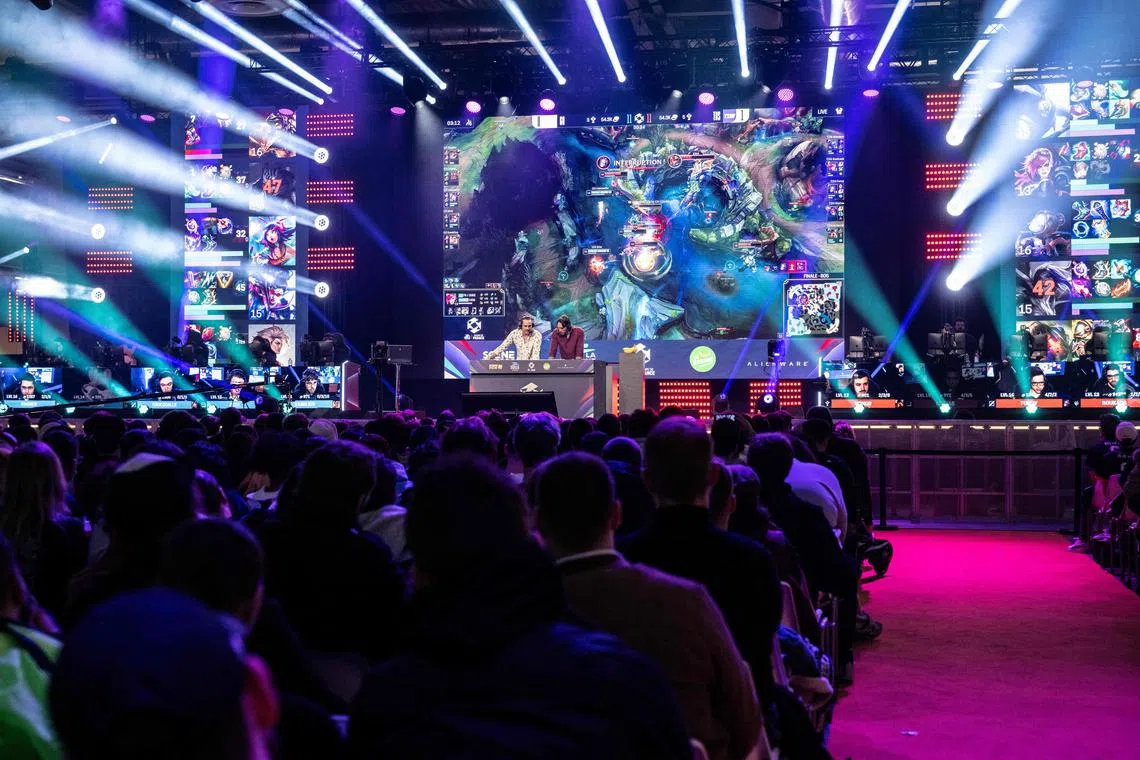 Visitors playing League of Legends at the Paris Games Week fair on Nov 1. The game's maker, Riot Games, plans to lay off about 530 employees.