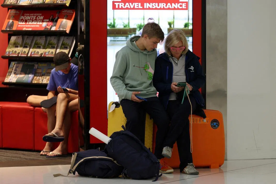 Stranded traveller Alessandra Giorgetti and her son Ascanio book an alternative flight to Milan after their Qatar flight via Doha was cancelled at Sydney Airport.