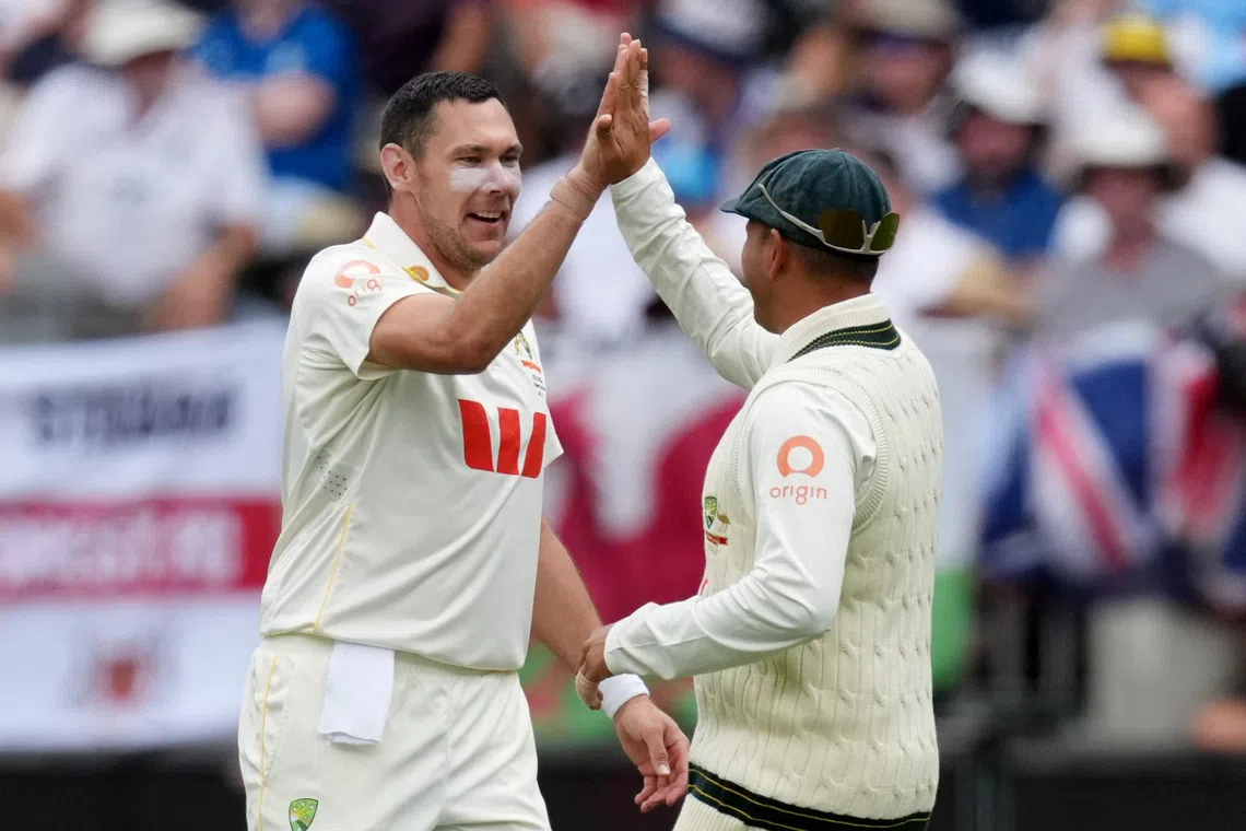Cricket - The Ashes - Australia v England - First Test - Perth Stadium, Perth, Australia - November 22, 2025 Australia's Scott Boland celebrates with Usman Khawaja after taking the wicket of England's Ollie Pope, catch taken by Alex Carey REUTERS/Asanka Brendon Ratnayake