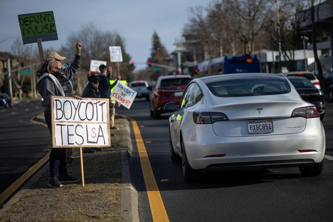 People protest against Elon Musk's role at Mr Trump's administration, outside of a Tesla dealership in Palo Alto, California.