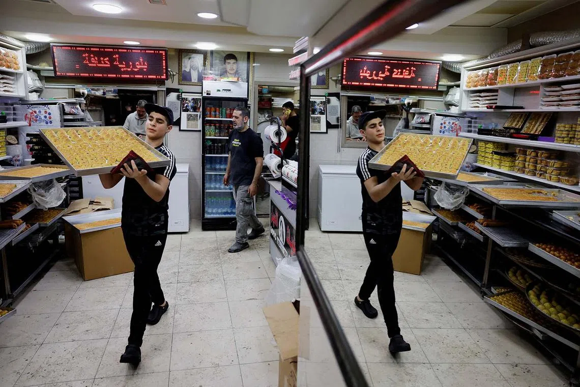 A worker carries traditional sweets as Palestinians prepare for the upcoming holiday of Eid al-Fitr marking the end of Ramadan, in Jerusalem Old City, March 27, 2025.REUTERS/Ammar Awad TPX IMAGES OF THE DAY
