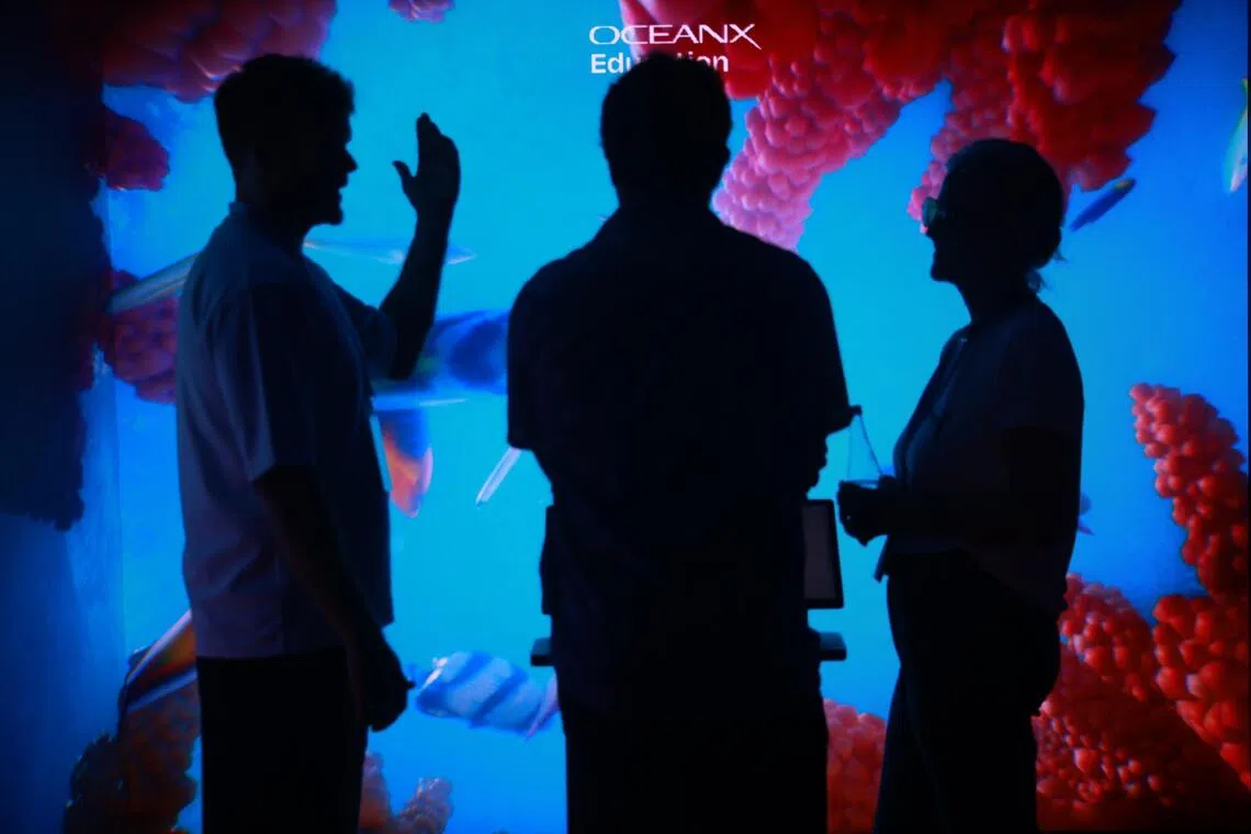 Attendees viewing a coral reef through an immersive display at the OceanX Summit aboard the research vessel.