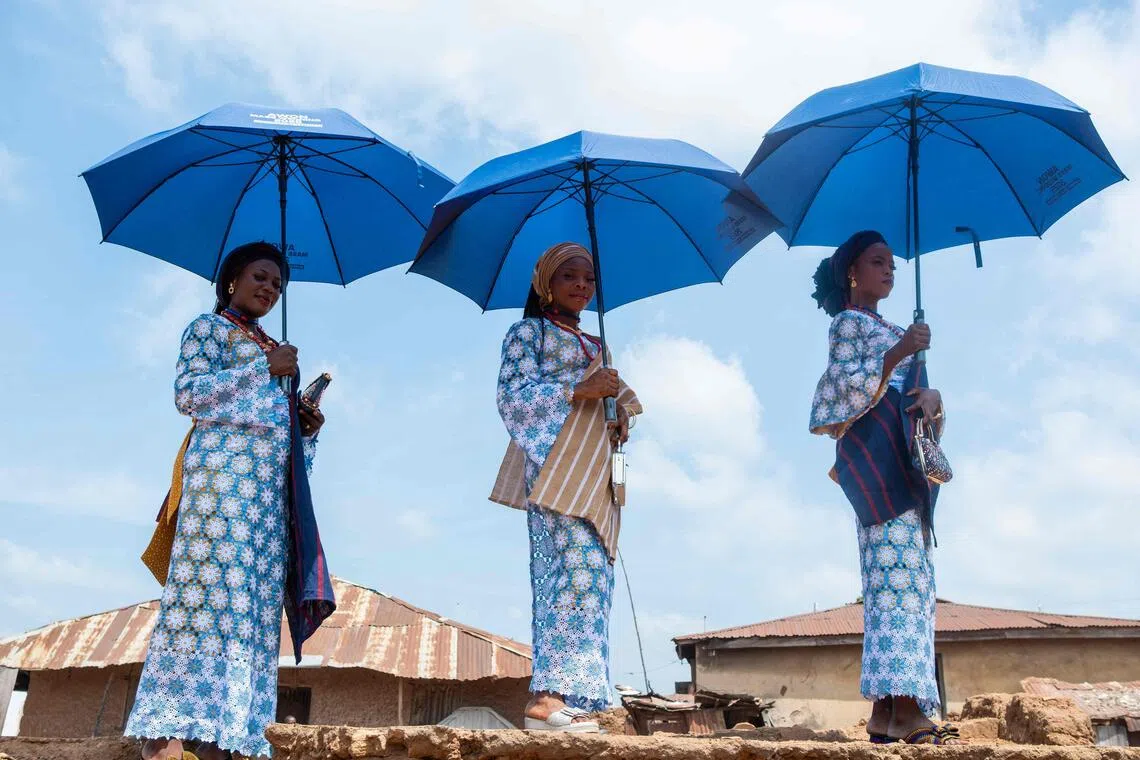 Brides pose for a photograph as they wait for the procession taking place during a mass wedding in Shao, Nigeria.