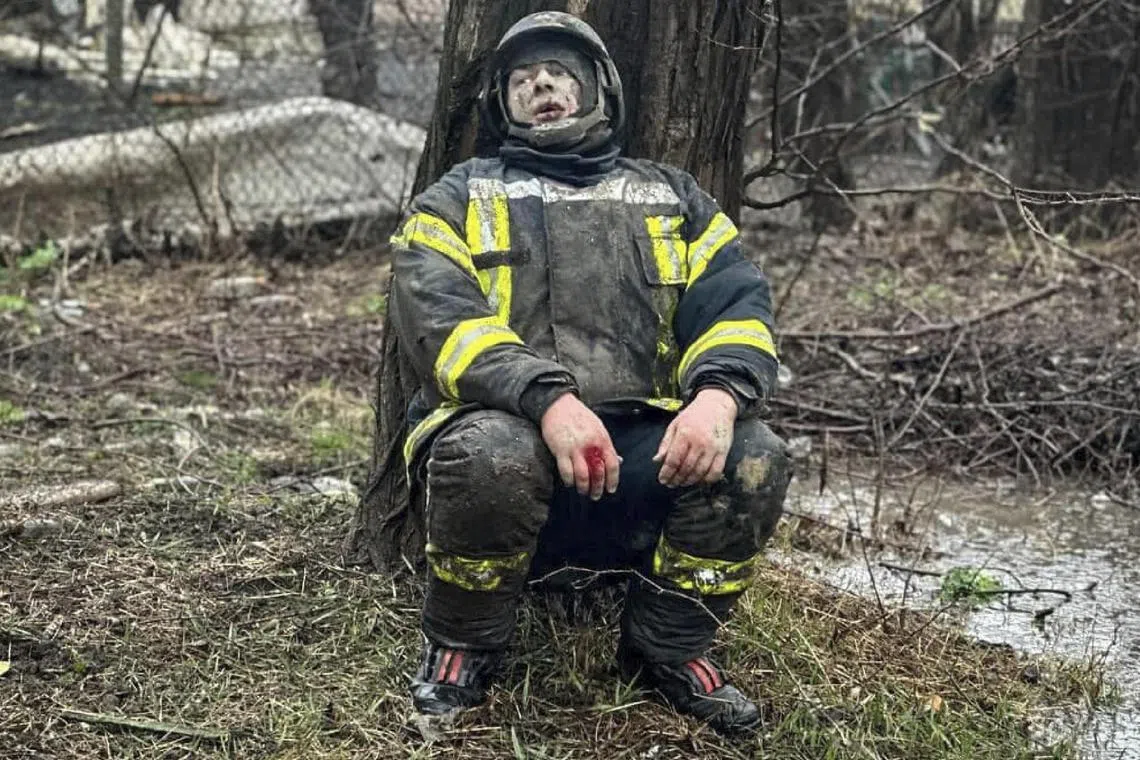 An injured rescuer sits next to a tree following a Russian missile attack on Odesa, Ukraine.