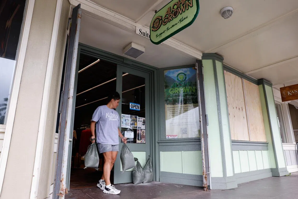 A person carrying bags exits a storefront with boarded-up windows.