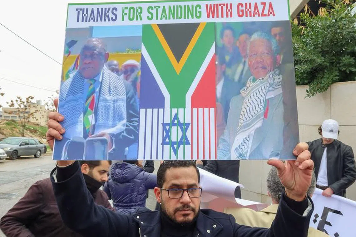 A demonstrator holds a sign during a protest as judges at The International Court of Justice (ICJ) in the Hague, hear a request for emergency measures to order Israel to stop its military actions in Gaza, in Amman Jordan January 11, 2024. REUTERS/Jehad Shelbak