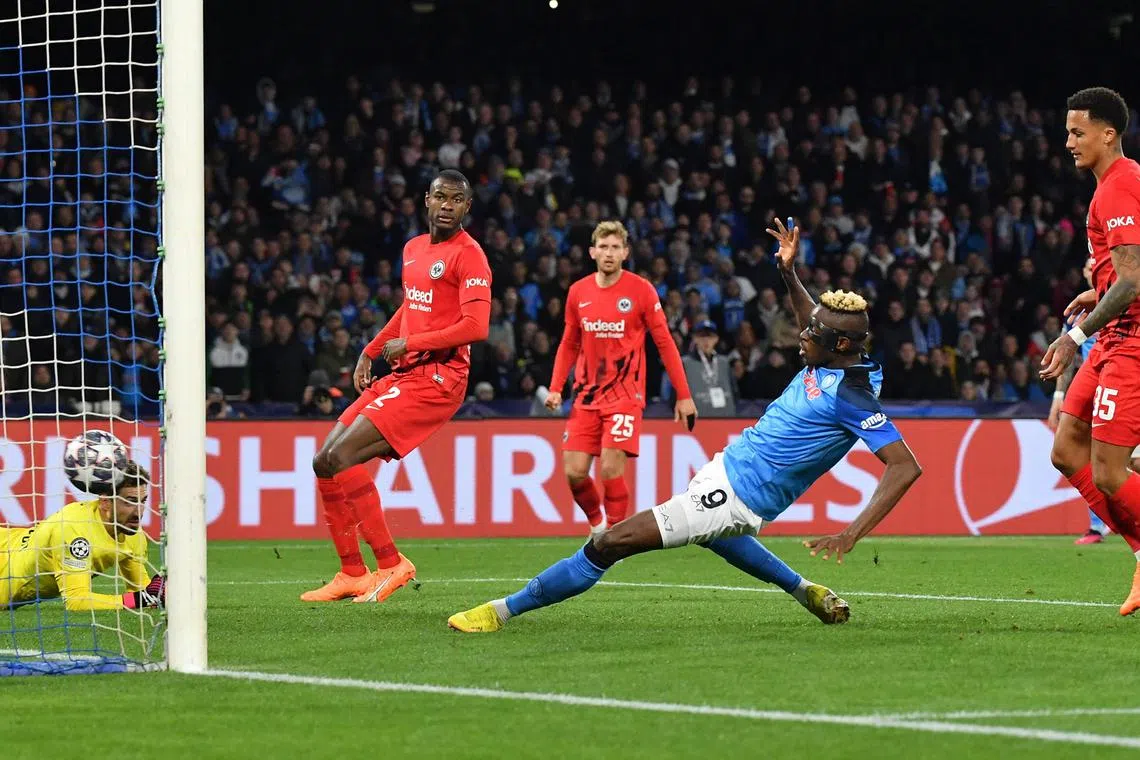 Napoli forward Victor Osimhen scoring his side's second goal past Frankfurt's German goalkeeper Kevin Trapp during the Champions League round of 16, second-leg football match at the Diego Maradona stadium in Naples.