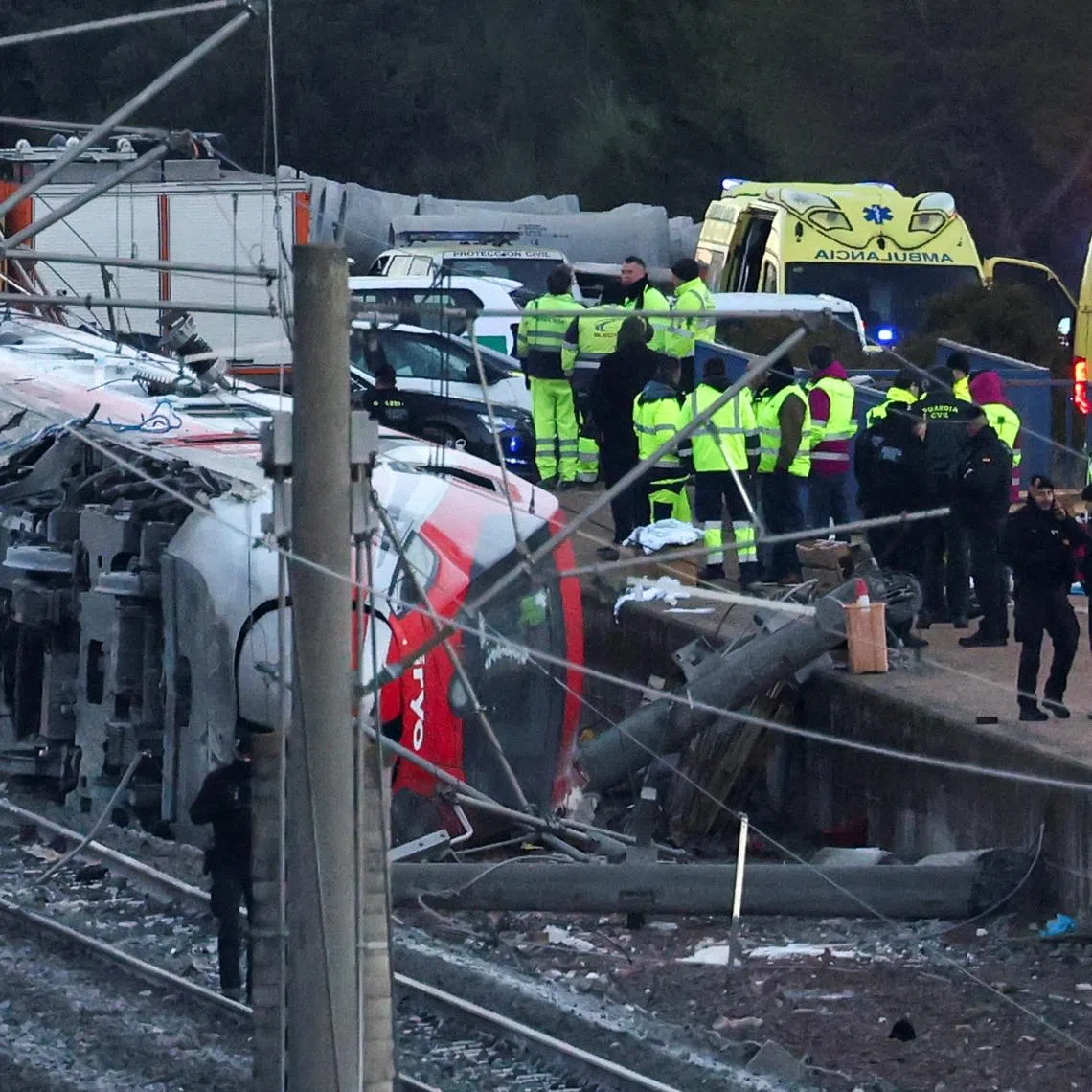 Members of the Spanish Civil Guard, along with other emergency personnel, work next to one of the trains involved in the accident, at the site of a deadly derailment of two high-speed trains near Adamuz, in Cordoba, Spain, January 19, 2026. REUTERS/Susana Vera