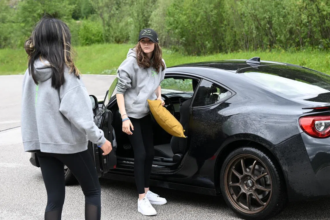 One of the participants from the More Than Equal Global Driver Development program walks with a cushion for elevation to one of the cars on the training track in Saalfelden, Austria, May 17, 2024. REUTERS/Angelika Warmuth