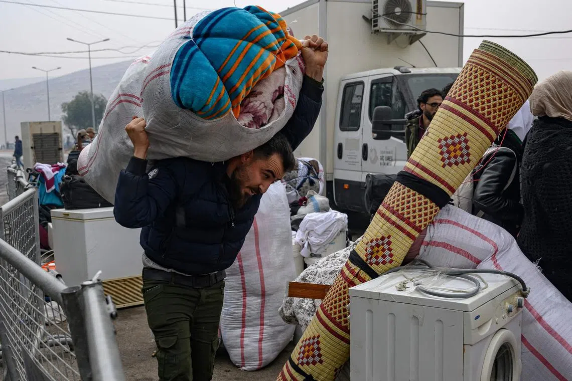 A Syrian living in Turkey carrying his belongings at a border crossing with Syria on Dec 12.